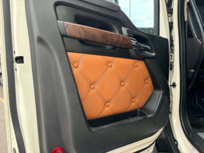 Interior of a Kenworth T680 door panel showing tan quilted leather insert with wood trim and black surrounding materials.