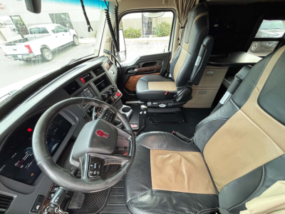 Kenworth T680 cab interior showing steering wheel, driver seat, and dashboard with center console in view.