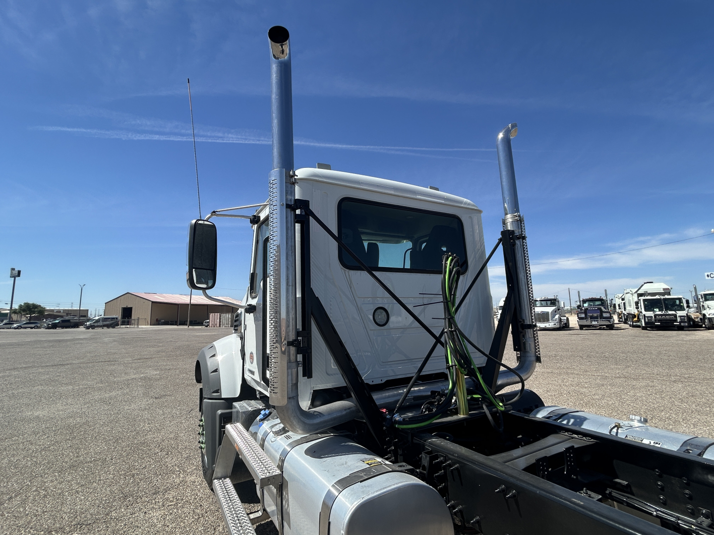 Truck cab on a 2027 Mack GR64FT chassis showing vertical exhaust stacks and exposed engine bay area with wiring harnesses.
