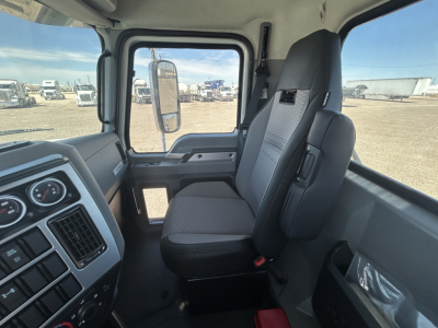 Cab interior of a 2027 Mack GR64FT truck showing steering wheel, dashboard gauges, and the front passenger seat.