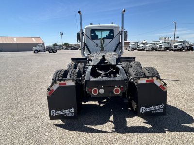 Rear view of a new 2027 Mack GR64FT daycab truck showing dual rear axles, mud flaps with Bruckners branding, and chassis components.