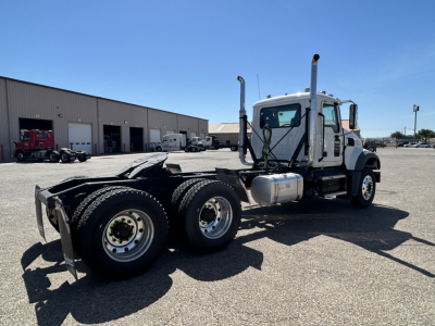 Mack GR64FT semi-truck tractor in a lot, white cab with dual exhaust stacks, large fuel tanks, rear wheels with six tires, no trailer attached.