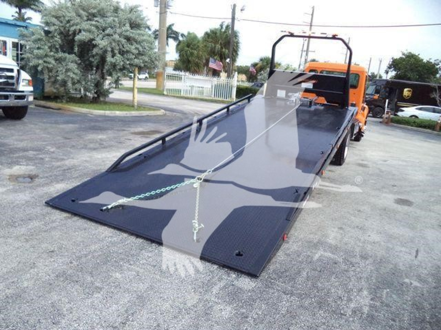 Kenworth T280 rollback truck with flatbed ramp and orange cab, showing loading platform and safety chains.