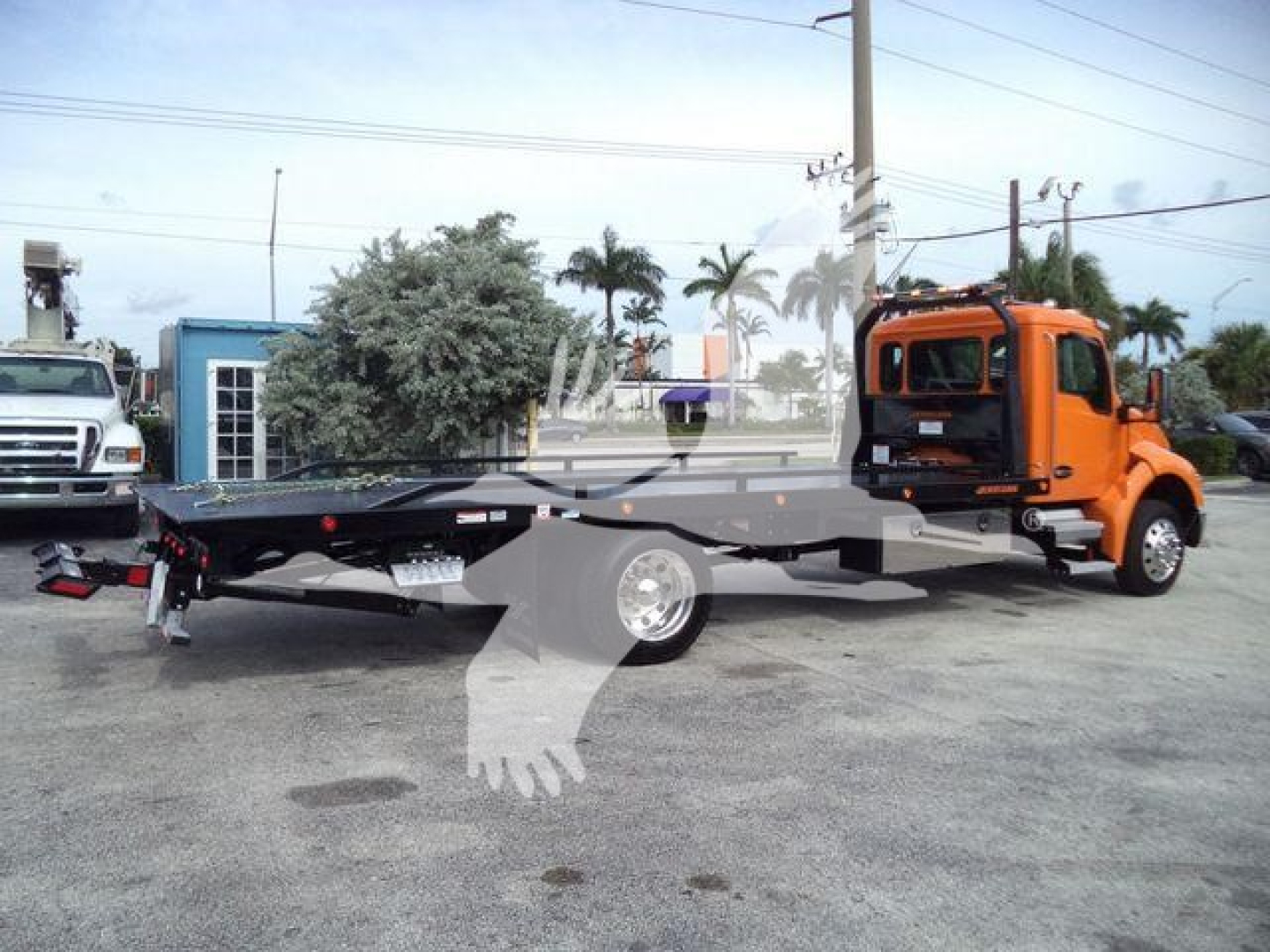 Kenworth T280 rollback tow truck side view showing orange cab and flatbed tow bed.