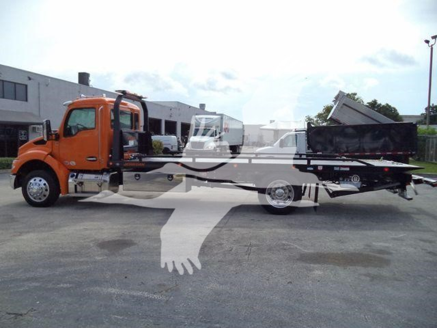 Kenworth T280 rollback truck in orange showing cab and flatbed with a dumped bed in rear, side view of the truck.