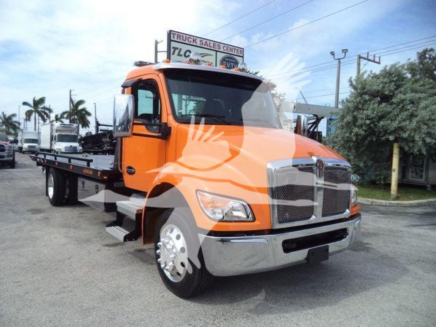 Kenworth T280 rollback tow truck in orange with flatbed, front grille, headlights, and side mirrors visible.