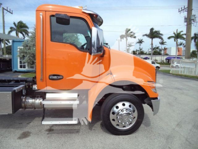 Orange Kenworth T280 rollback truck cab side view showing front wheel, side steps, and operator door with black handle.