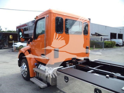 Truck cab side view showing bright orange Kenworth T880 chassis with side steps and fuel tanks; orange body with white and gray graphics and large mirror housings.