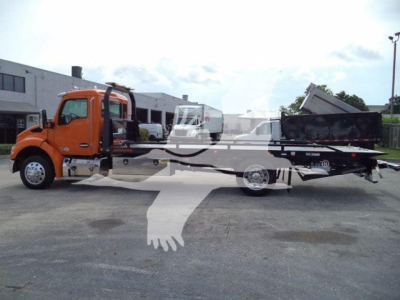 Kenworth T280 rollback truck in orange showing cab and flatbed with a dumped bed in rear, side view of the truck.