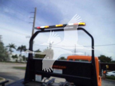 Truck bed and cab with rollover frame, orange Kenworth T280 in a rollback configuration, rear view showing light bar on top and window guard.