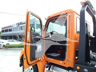 Truck cab exterior with open orange doors showing the cabin interior and step seating, Kenworth T-series style, rollback equipment attached.