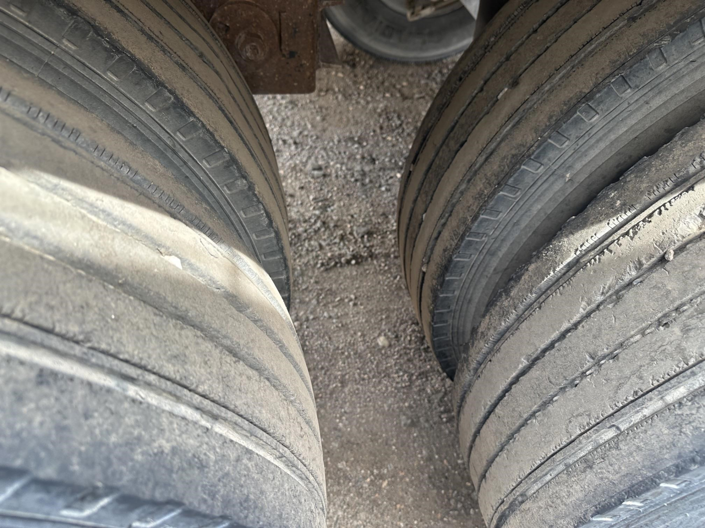 End dump trailer dual tires showing wear on tread and gap between axles in frame area.
