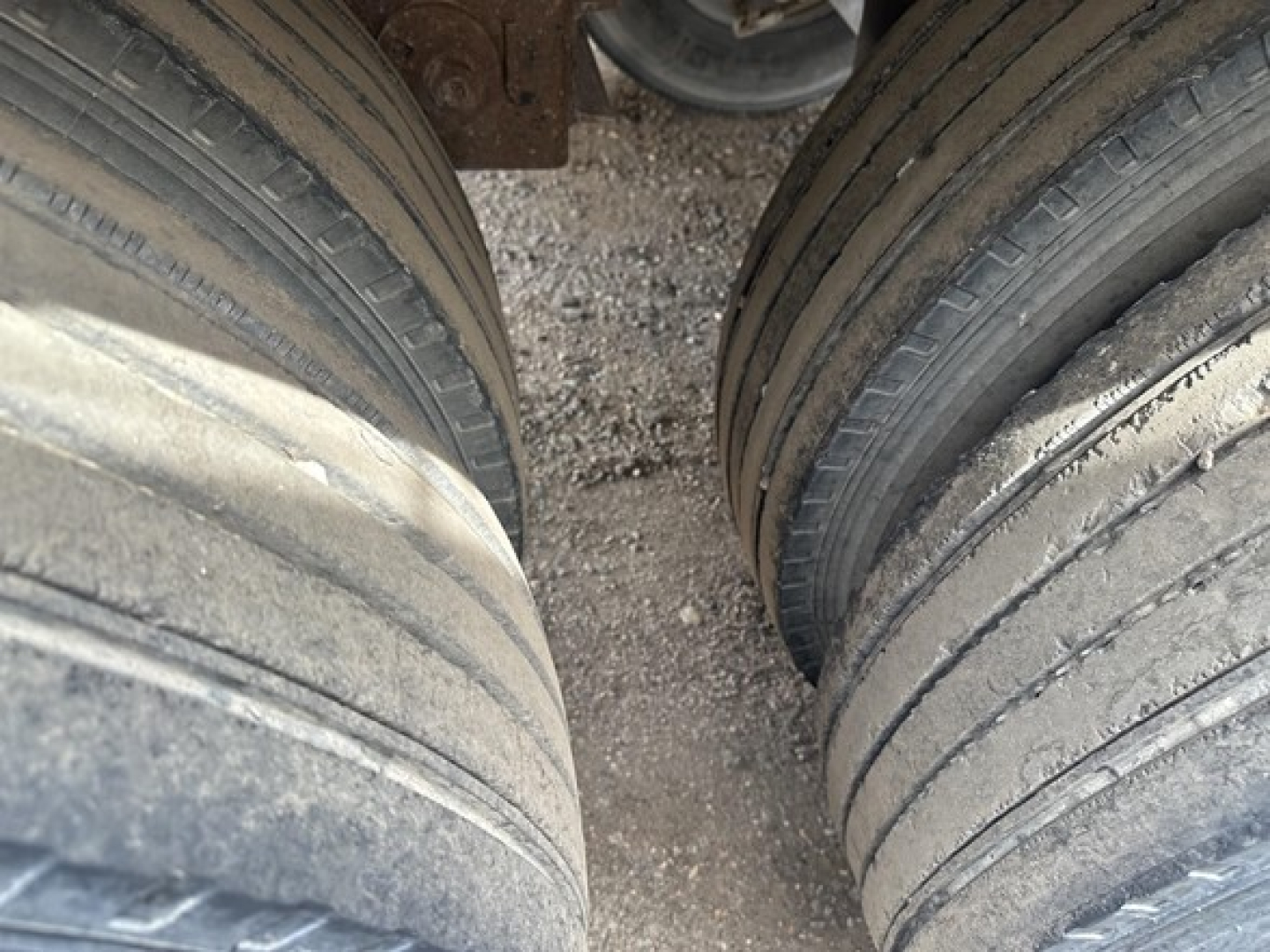 Dual rear trailer wheels and mud/dust on tires of a 2001 Vantage frameless aluminum end dump trailer showing tandem axle tires and gaps between wheels.