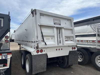 Dump trailer showing rear view of a frameless aluminum end dump with dual axles and mud flaps.