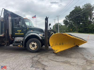 Truck side view showing a green 2006 International WorkStar 7600 dump truck with a large yellow front plow attached, decals read TOWN OF BROADALBIN, plow blade in front, overcast sky