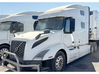Truck: 2020 Volvo VNL 760 conventional sleeper, white with aerodynamic hood, side mirrors, and attached trailer behind. Front grille, bumper guard, and wheel hubs visible.