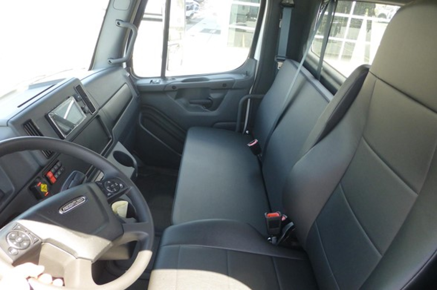 Freightliner M2 106 cab interior showing dashboard and front bench seat with steering wheel