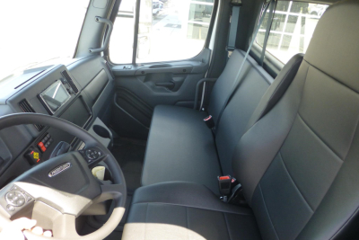 Interior of Freightliner M2 106 Plus cab showing front dash and bench seating in driver area.