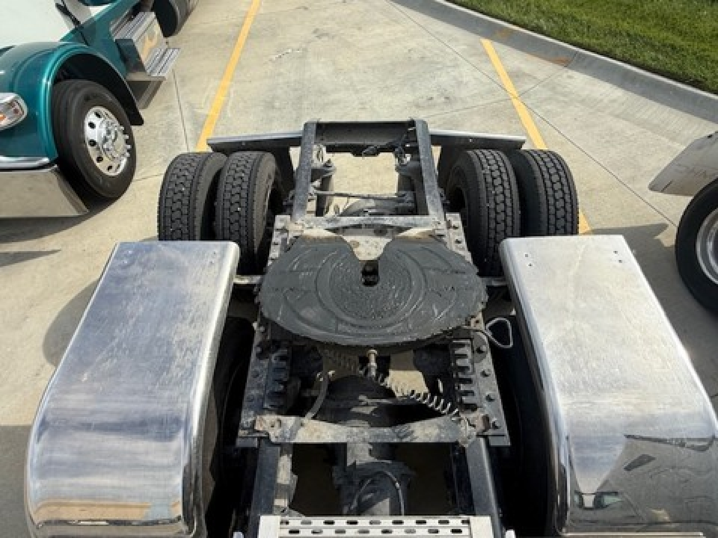 Kenworth chassis and rear cab area showing frame rails, dual rear axles, and aluminum fuel tanks; visible components include suspension, drivetrain mounting, and missing cab at rear.