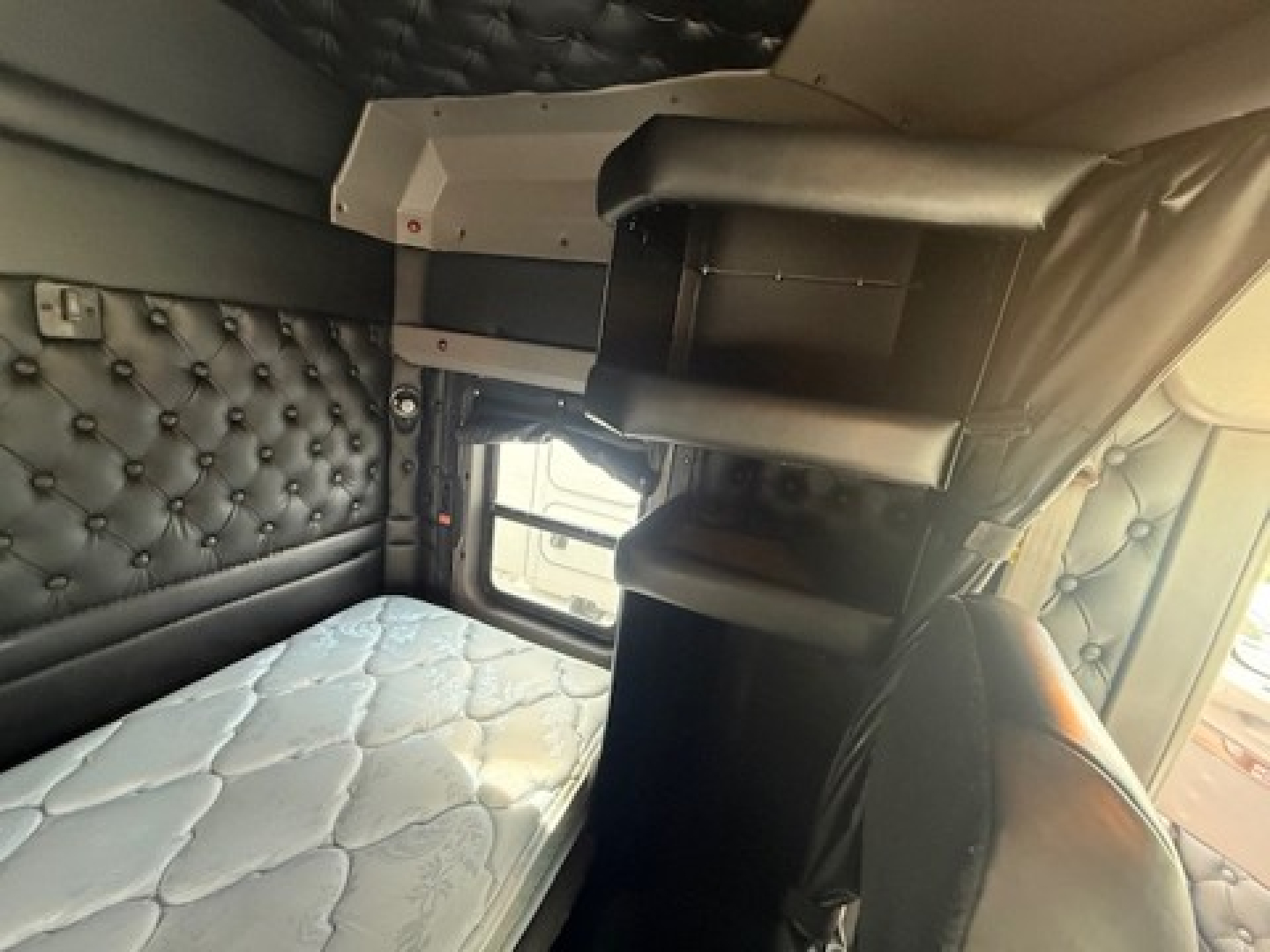Kenworth W900L sleeper cab interior with bunk bed and storage shelves.