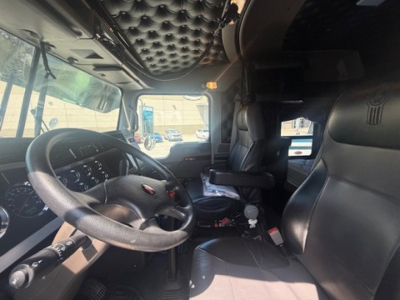 Kenworth W900L truck cab interior showing steering wheel, dashboard, and driver's seat with diamond-tufted headliner.