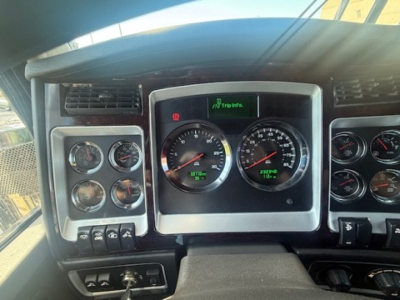 Kenworth W900L dash showing gauge cluster and instrument panel with multiple switches and vents.