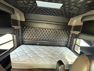 Kenworth W900L sleeper cab interior showing quilted headliner, diamond-tufted side panels, and a padded bed with mattress top.