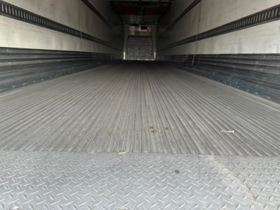  trailer interior with ribbed metal floor and sidewalls, empty reefer trailer with rear door opening visible