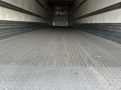 Great Dane reefer trailer interior showing ribbed metal floor and sidewalls; empty cargo space with rear doors in distant view.