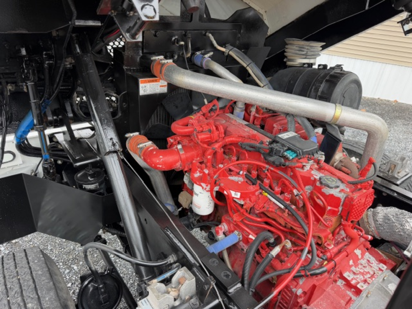 Red Capacity TJ5000 engine with surrounding components and hoses in a truck's engine bay, showing a prominent red engine block and intake tubing.