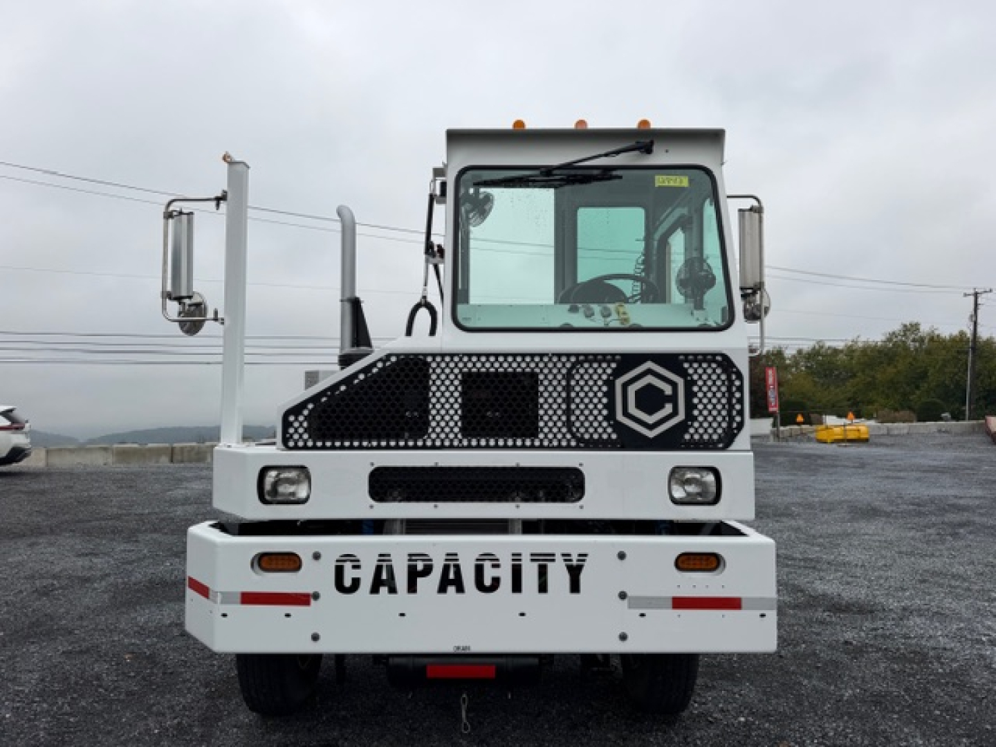 Front view of a Capacity TJ5000 yard truck showing the grille, windshield, and bumper with the word CAPACITY on the bumper and DOT/industrial markings.