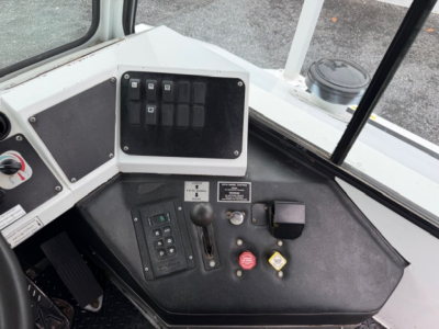 Truck cab dashboard with control panel, switches, and emergency stop; visible labels and gauges on the dash.