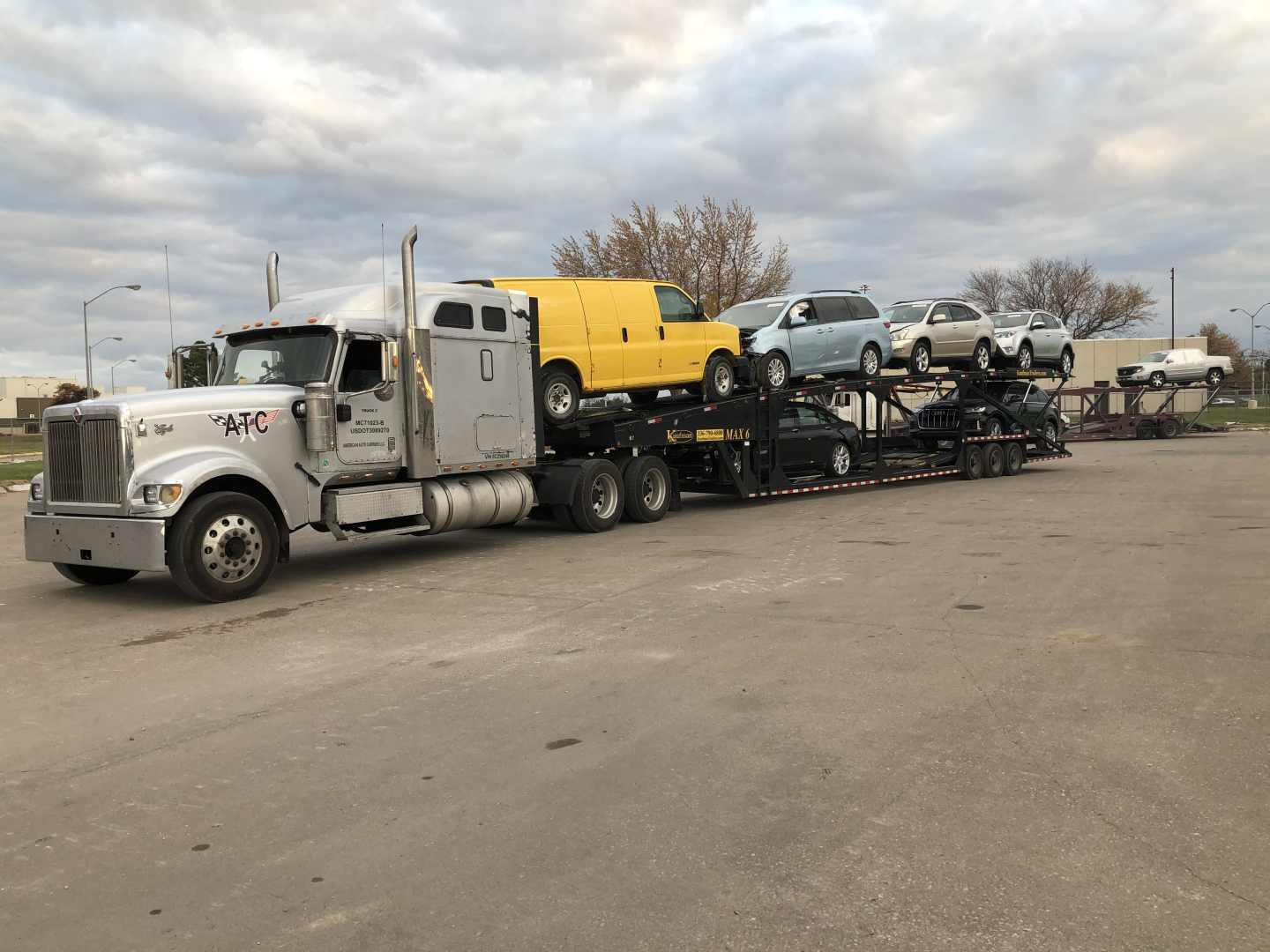 Semi truck cab and multi-car trailer transporting several small vehicles including a yellow van and other cars.