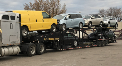 Carrier trailer with multiple cars on a Kaufman Max 6 car car carrier trailer, yellow van on top deck and other vehicles secured on the lower deck.