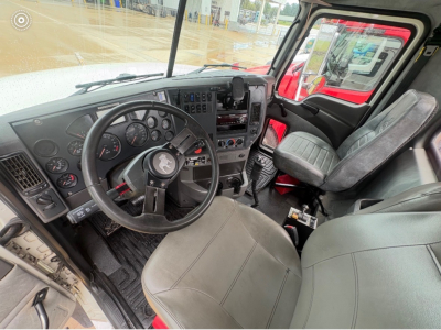 Truck cab interior showing steering wheel, dashboard with gauges, and driver seat in a Mack CHU613 truck daycab.