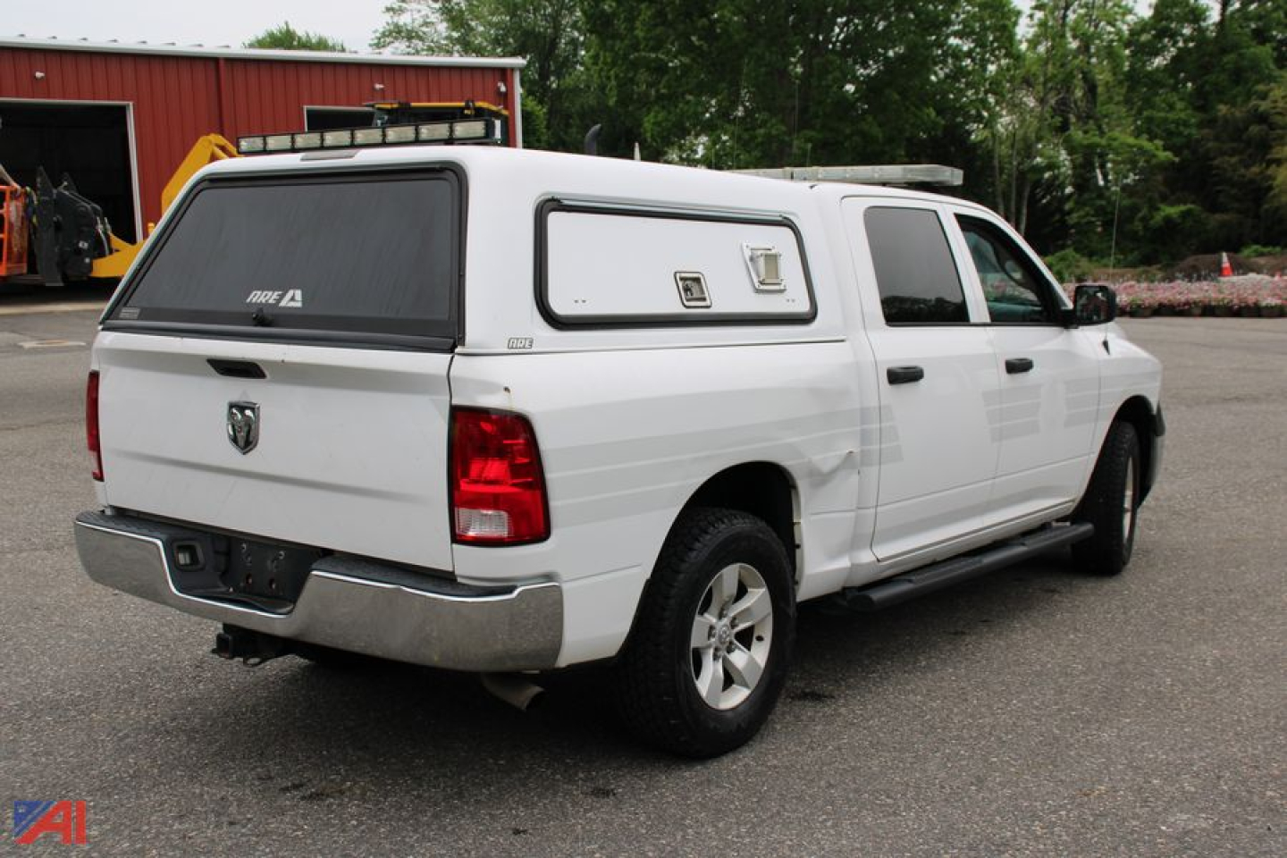 Ram 1500 crew cab pickup with white cap/aerodynamic camper shell, rear three-quarter view showing cap windows and taillights.