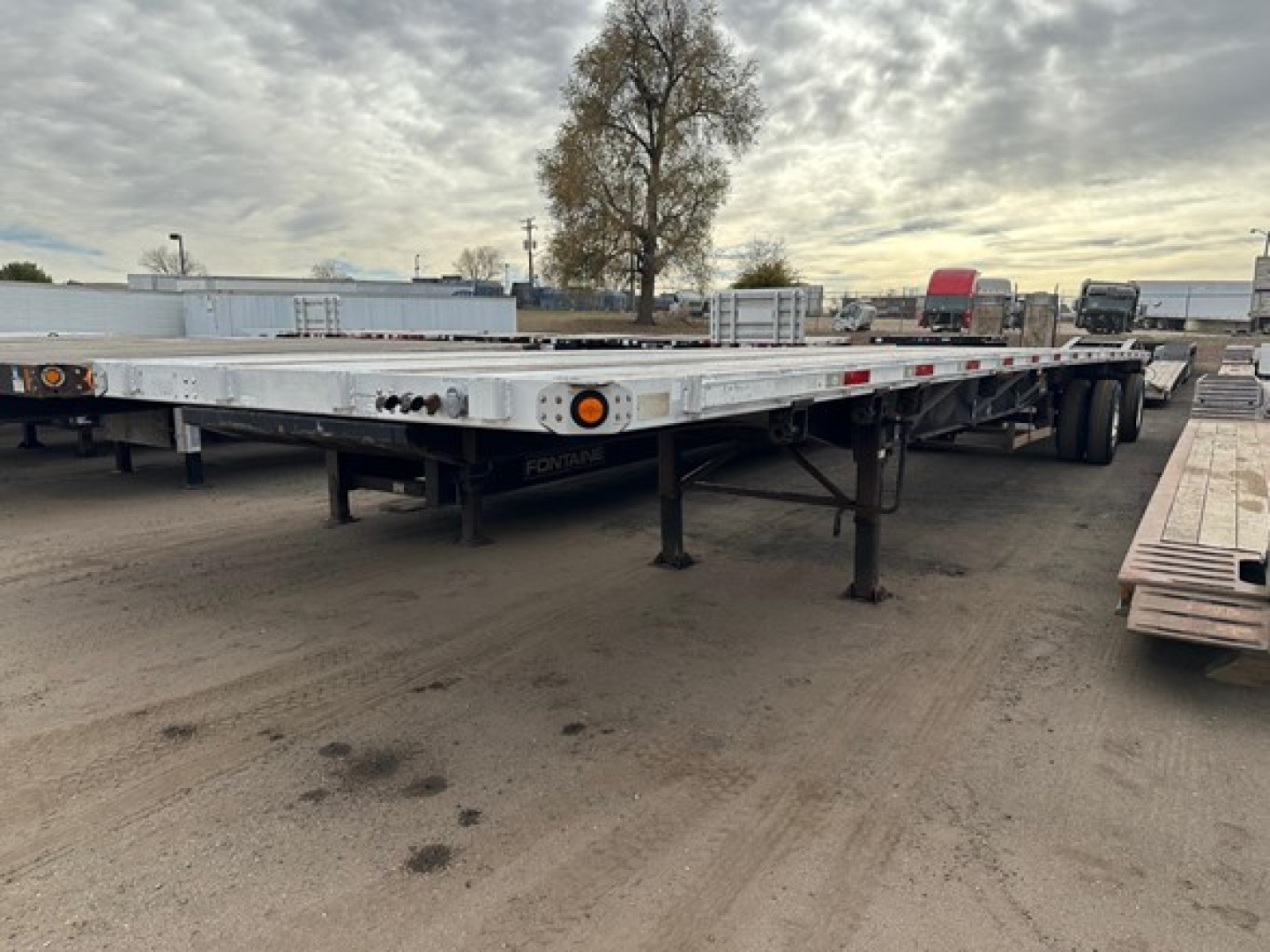 Flatbed trailer from side view showing low-profile frame and landing gear undercarriage, 2015 Utility 4000AE with dual axle, used category.