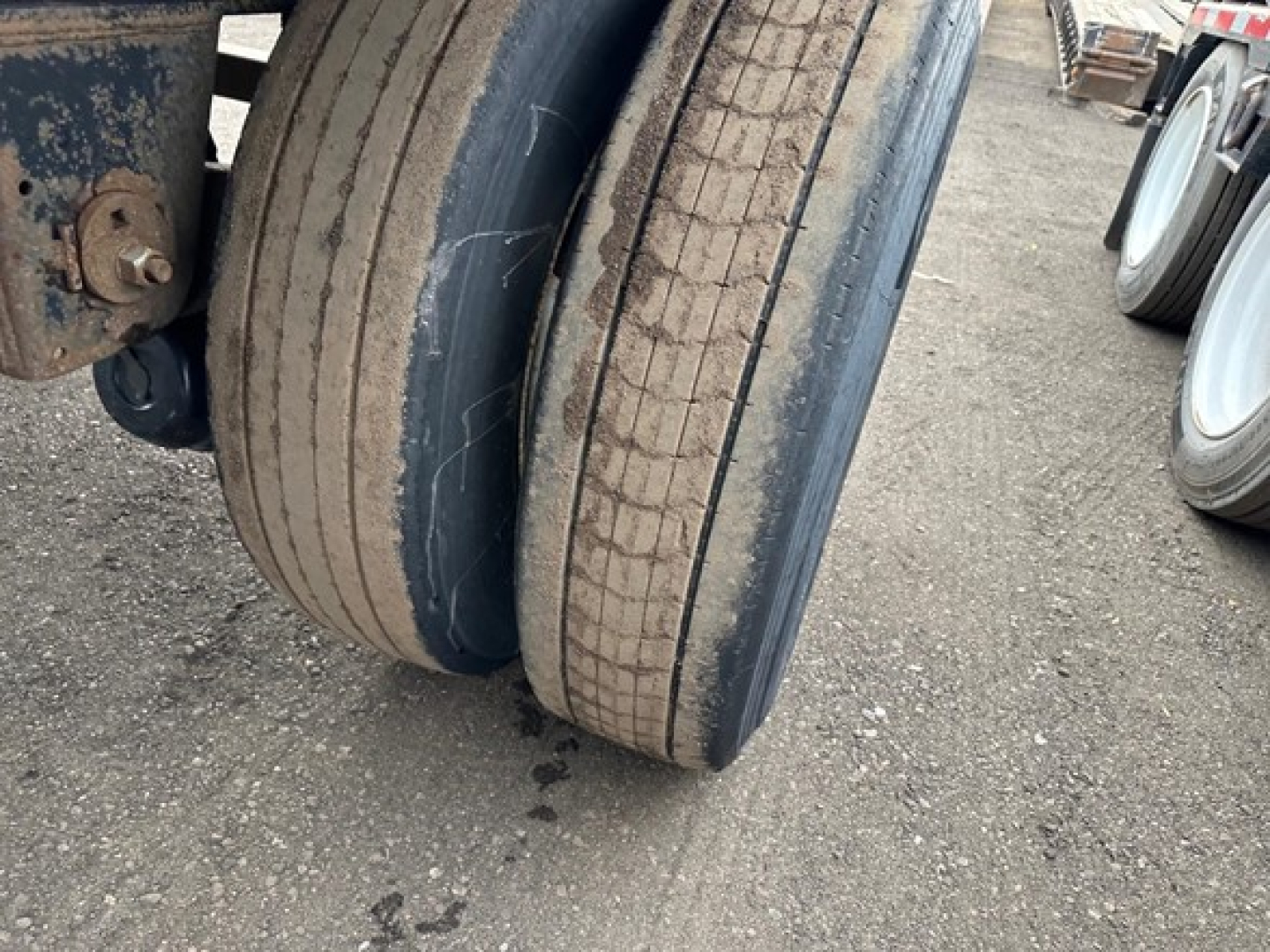 Trailer dual axle tires with worn treads on a flatbed trailer, visible rims and part of the frame; no other text visible.