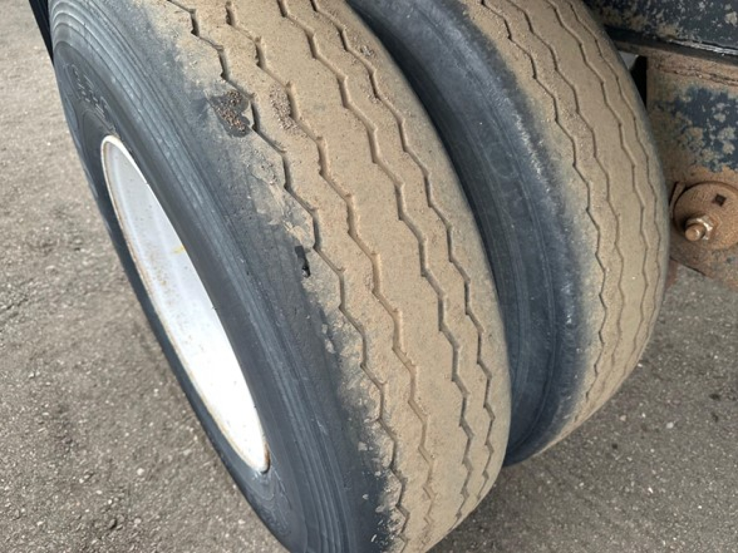Rear dual trailer tires with tread pattern visible on a utility flatbed trailer.