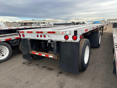 Trailer rear with dual rear axles and mud flaps, Utility flatbed trailer with taillights; shows aluminum frame with red reflectors and black fenders.
