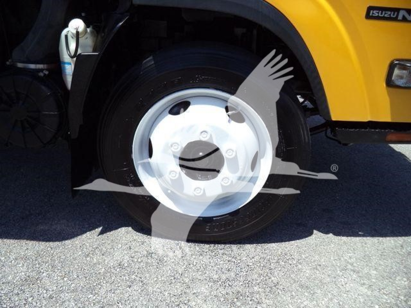 Isuzu NPR HD wheel and fender area with yellow body, visible tire and front wheel cover.