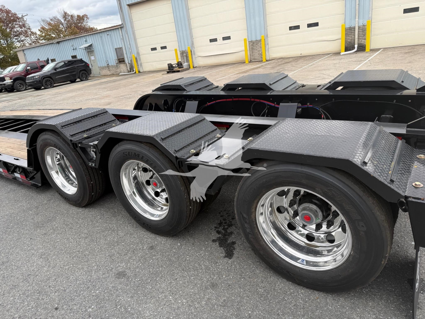 Trailer underside and tires of a Fontaine 55Lcc W lowboy trailer showing dual tandem axles with chrome rims and black textured fenders.