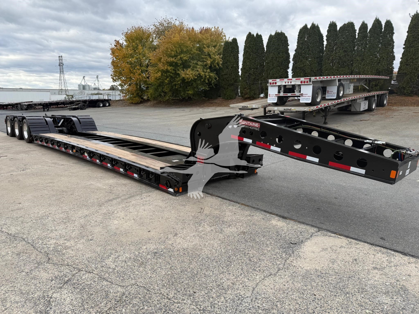 Trailer chassis and long lowboy deck showing Fontaine 55Lcc W trailer with black steel frame and multiple axles.