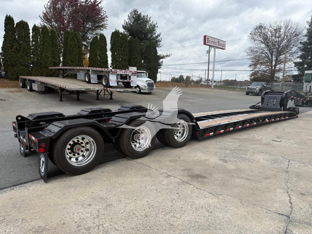 Lowboy trailer from side showing long flat deck with multiple axles and wheels, Fontaine 55Lcc W model designation not visible, open yard with other trailers in background.