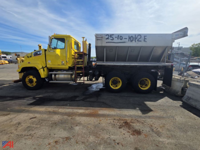 Truck-mounted stone spreader in yard showing Western Star 4700 SF cab and large dump bed with yellow wheels.