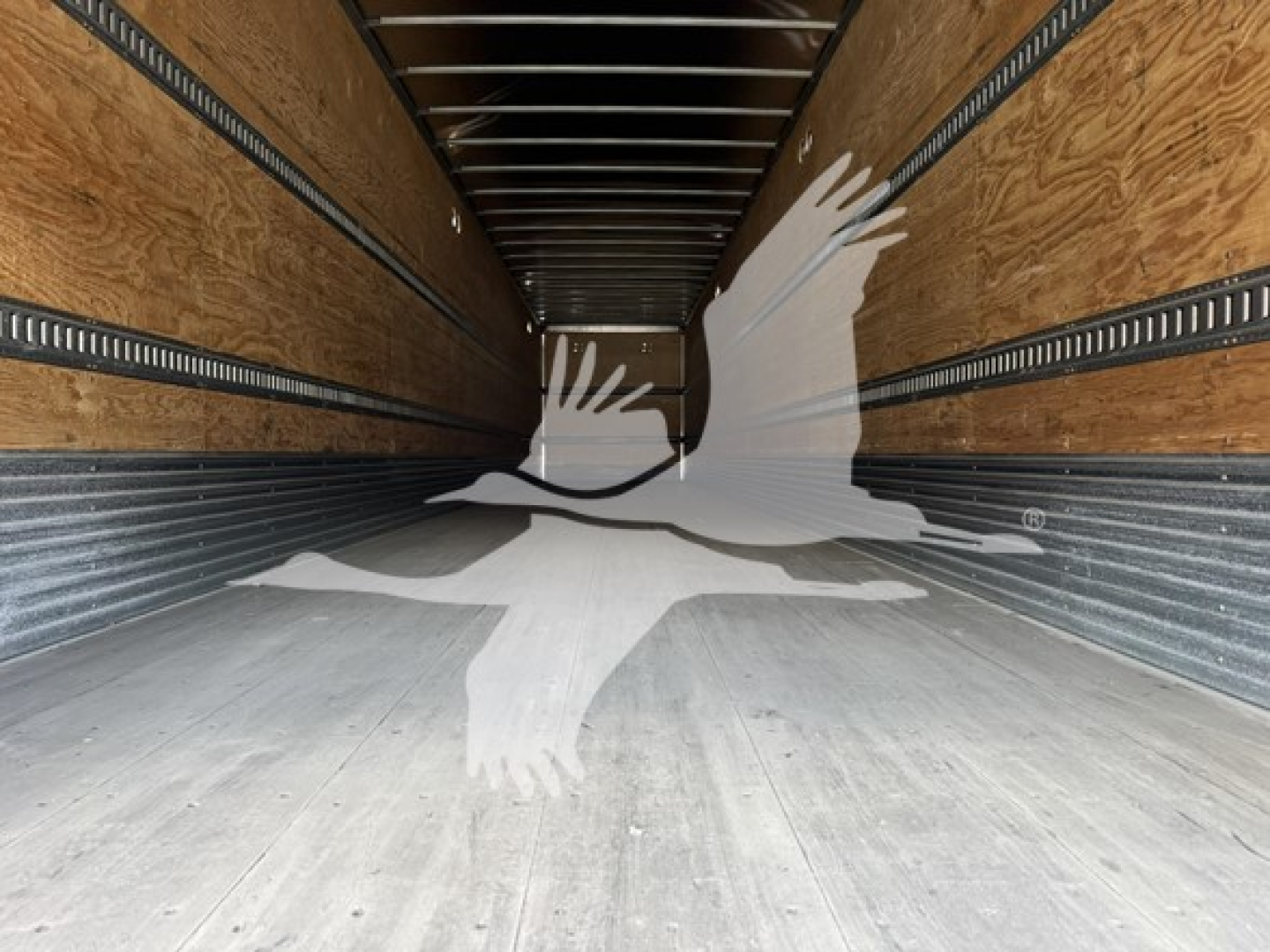 Interior of Hyundai roll door van trailer showing wooden side walls, metal rails, and concrete floor; empty cargo area with long perspective.