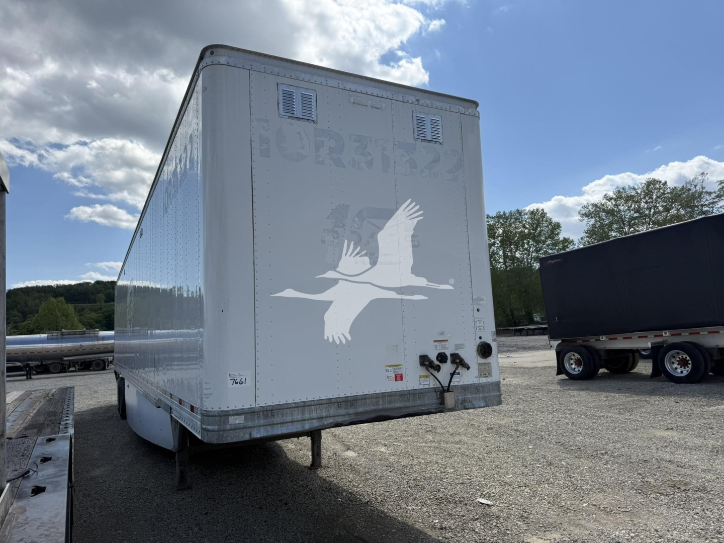 Trailer rear view of a Hyundai roll door van, with emblem and LED lights; white exterior with faded graphics and rear bumper area.