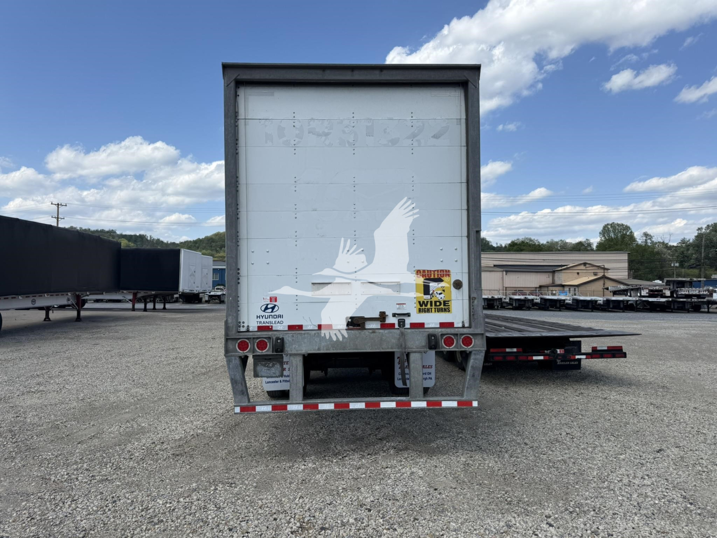 Rear view of a Hyundai roll door van trailer showing taillights, reflective safety decals, and rear bumper. Visible text includes a Hyundai logo and a white roll-up rear door.