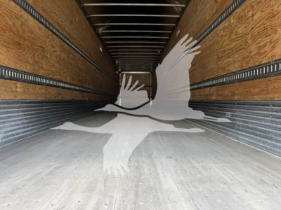 Interior of Hyundai roll door van trailer showing wooden side walls, metal rails, and concrete floor; empty cargo area with long perspective.