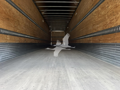 Interior of a Hyundai roll door van trailer showing wooden sidewalls, metal rails, and empty cargo area with a watermark logo in the center.